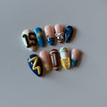 Hand-painted football press-on nails in blue and gold with a jersey number and football accent nail