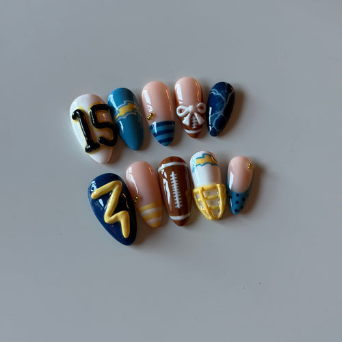 Hand-painted football press-on nails in blue and gold with a jersey number and football accent nail