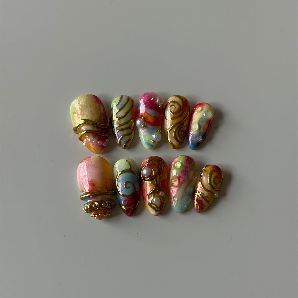 Hand-painted pastel press-on nails with sculpted gold chrome details and 3D embellishments